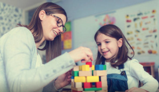 A teacher interacting with a young child building blocks. 