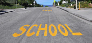 A road with "school" painted in yellow letters on it 