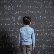 young boy standing in front of chalkboard with complicated math equations