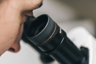 closeup on person looking into the eyepiece of a microscope